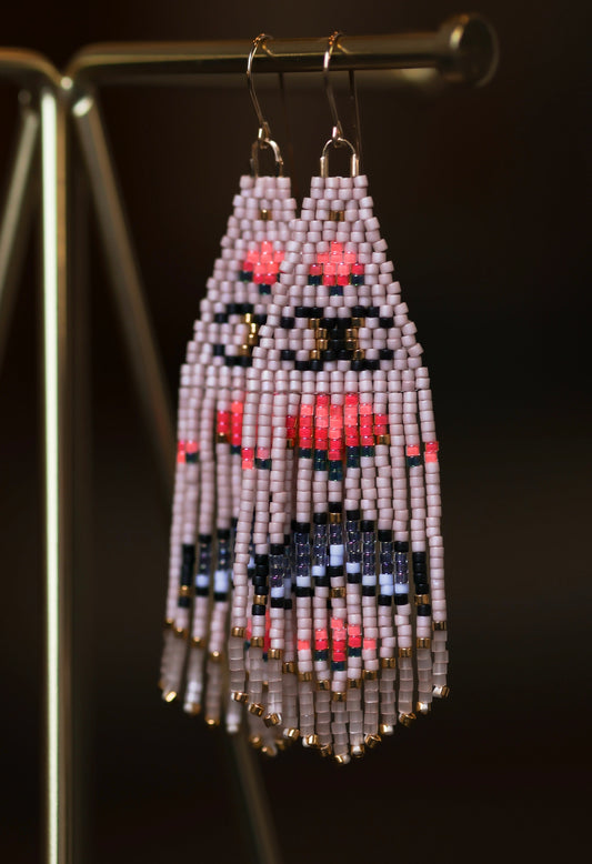Beaded earrings on a stand against a dark background