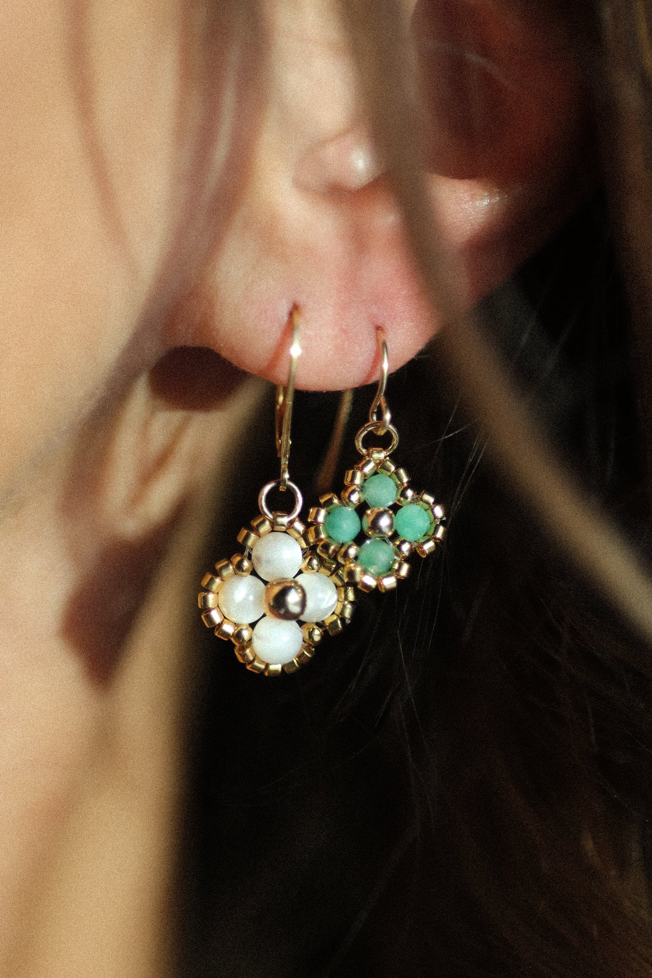 Close-up of a person wearing beaded earrings with green and white beads.
