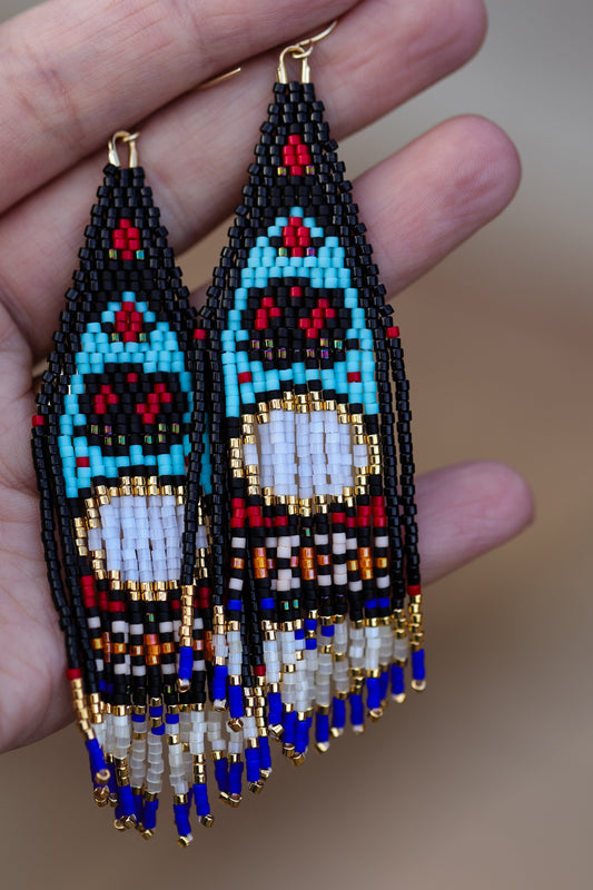 Colorful beaded earrings held between fingers against a neutral background