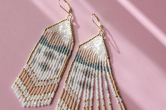 Beaded earrings with gold accents on a pink background