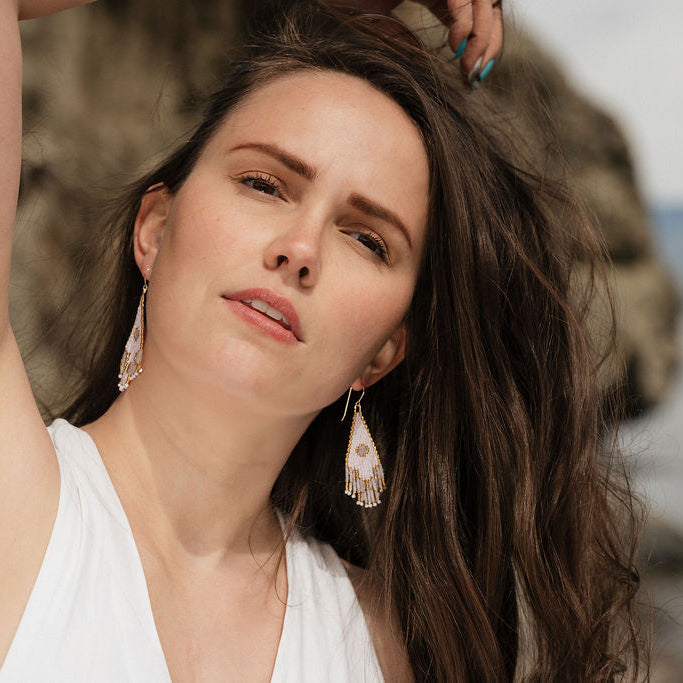 Woman in white top wearing beaded long earrings