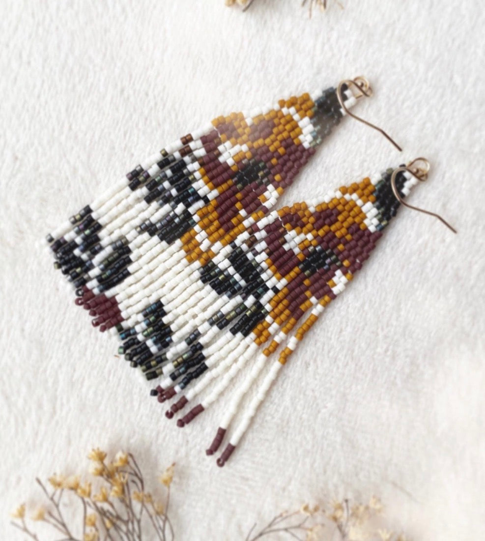 Beaded earrings on a white background with dried flowers.