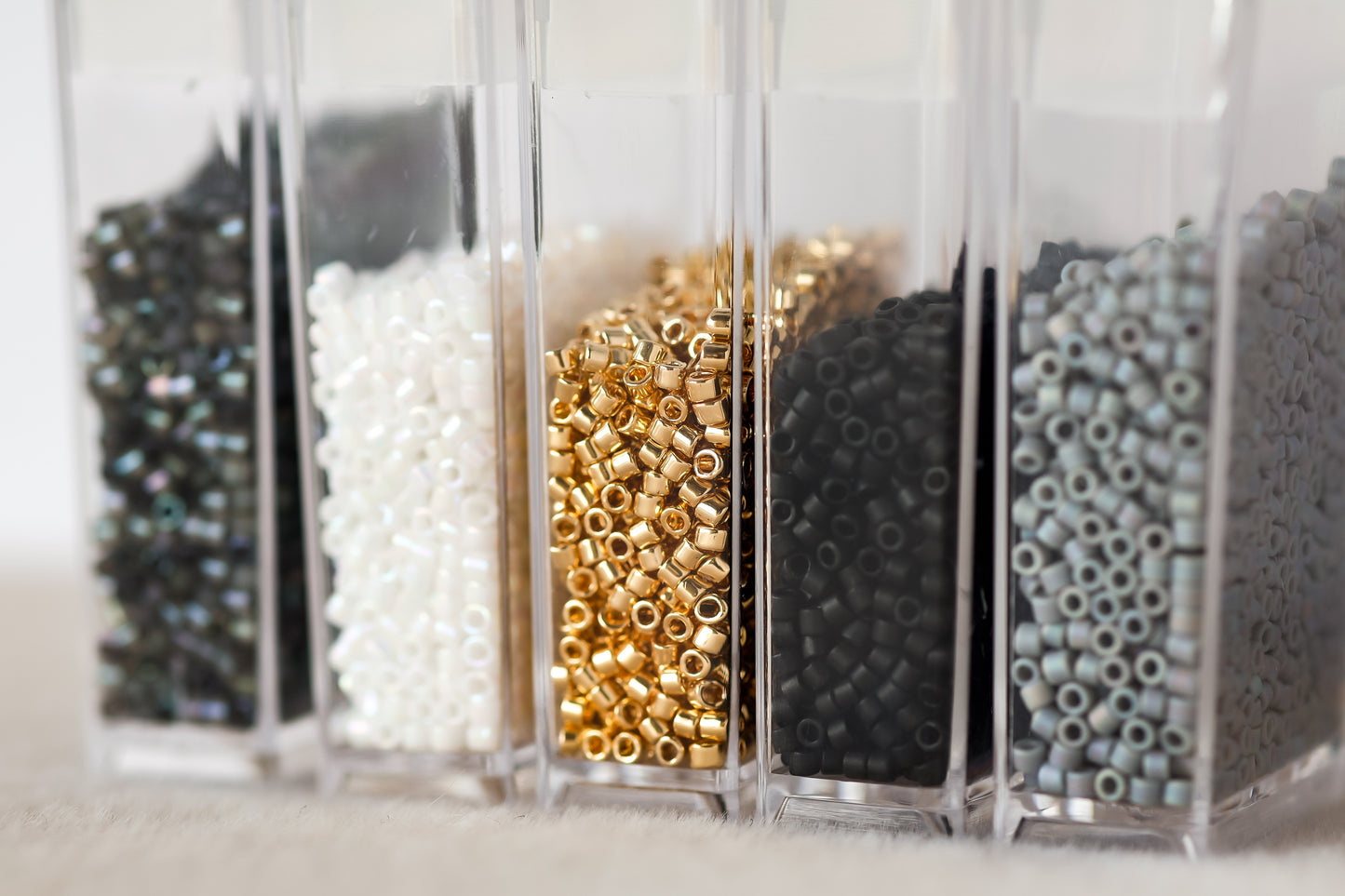 Clear containers with various types of beads on a light background