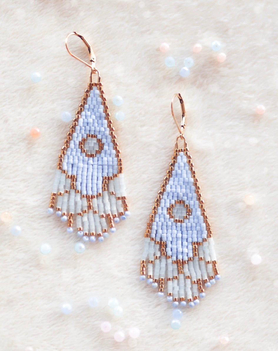 Handmade beaded earrings on a textured beige background