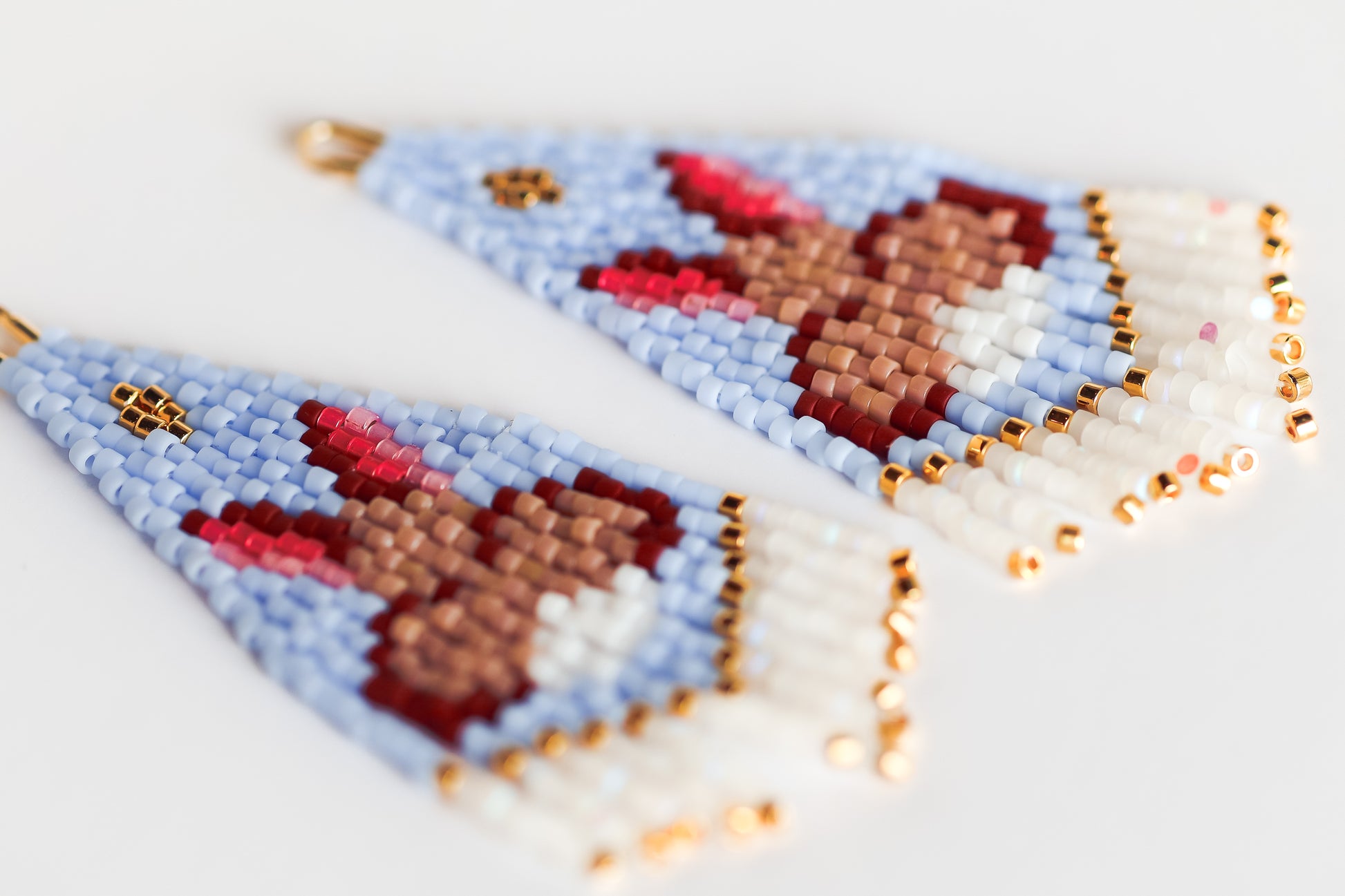 Two beaded triangle earrings with a bunny design on a light background