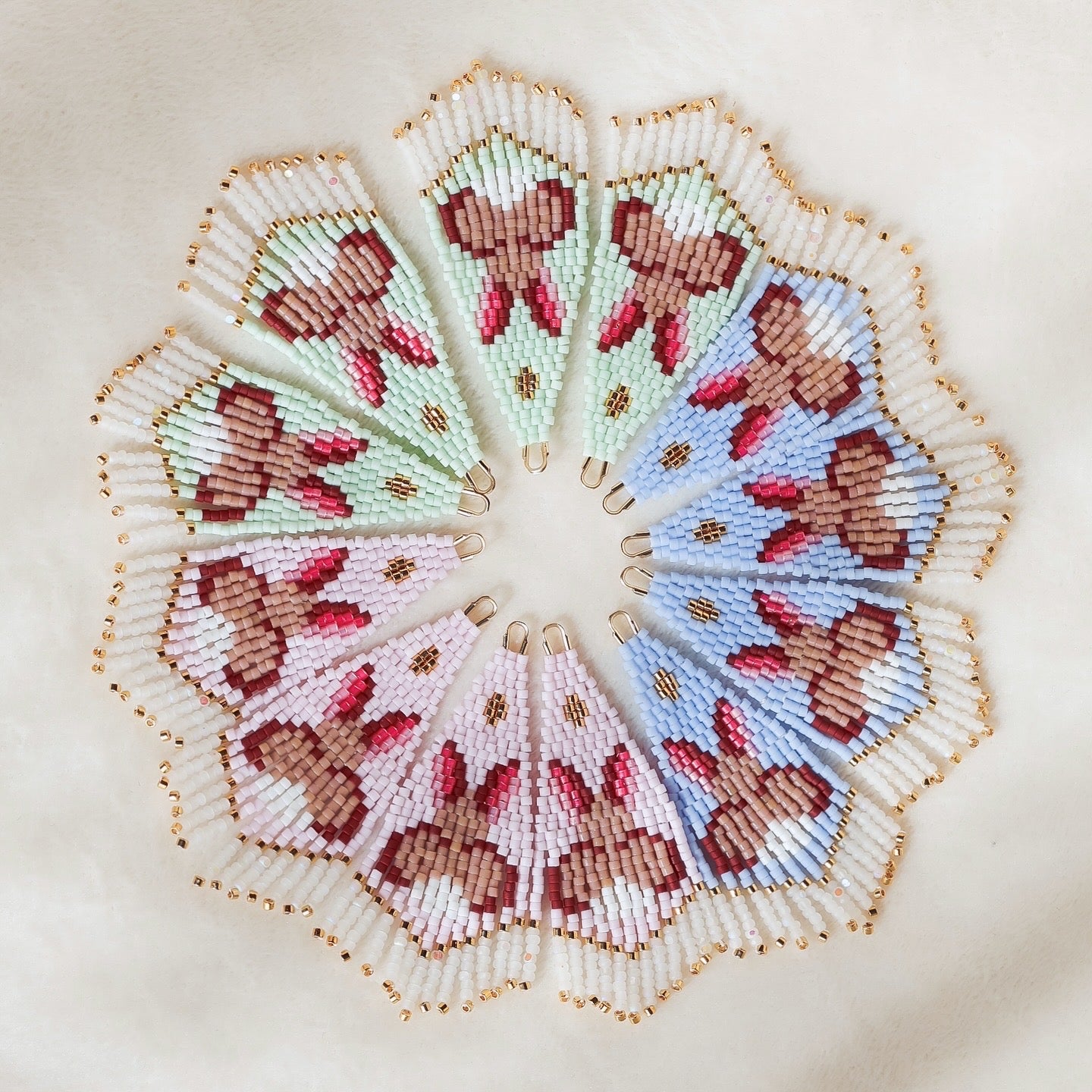 Twelve handmade beaded earrings in a circular design with bunny pattern