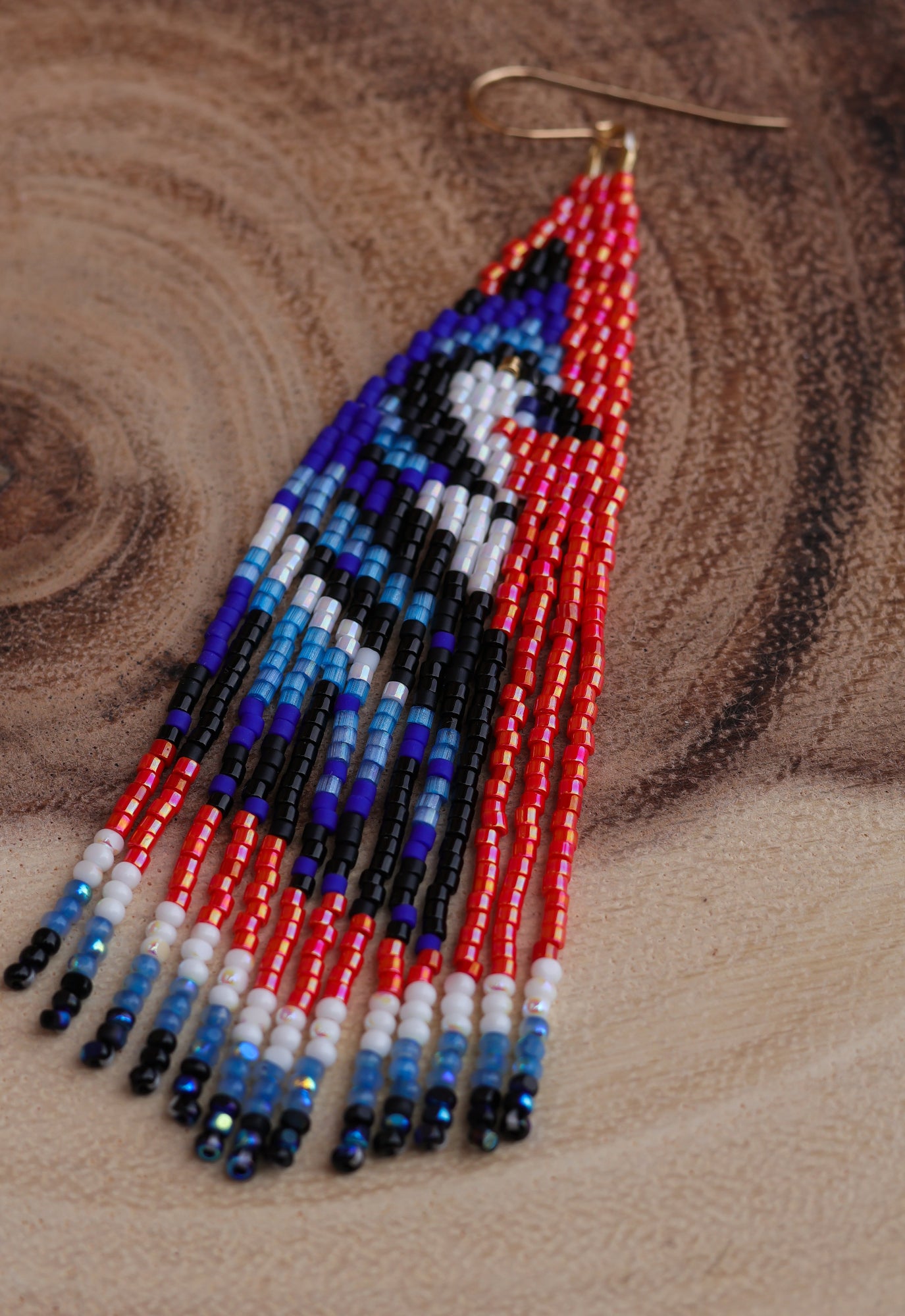 Beaded earrings with a bird design on a wooden surface