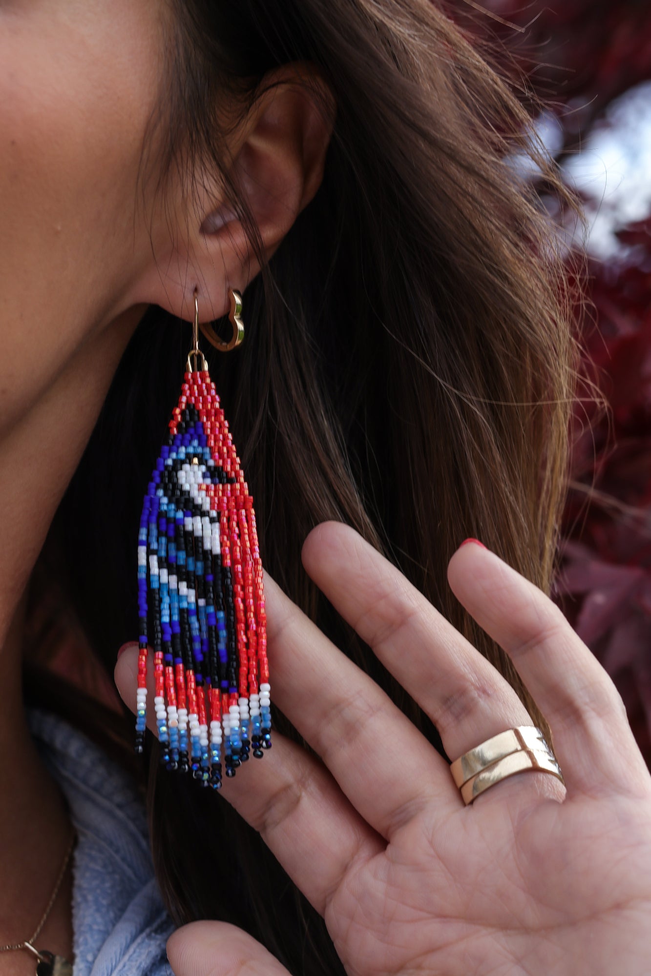 Close-up of a person wearing colorful beaded earrings with a blurred background