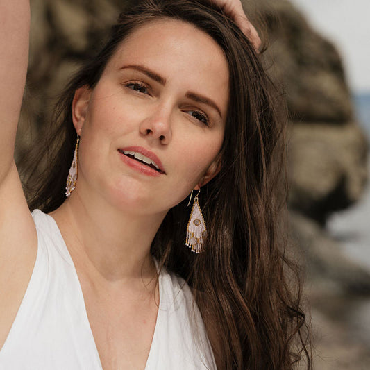 Woman in white top wearing beaded earrings