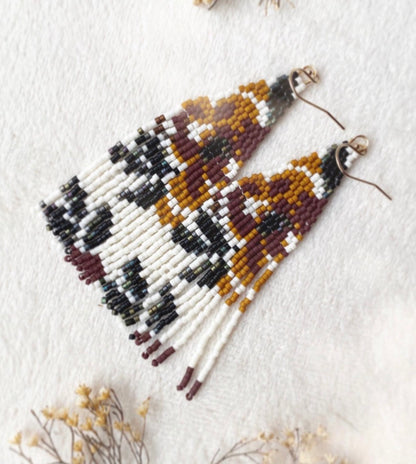Beaded earrings on a white background with dried flowers.
