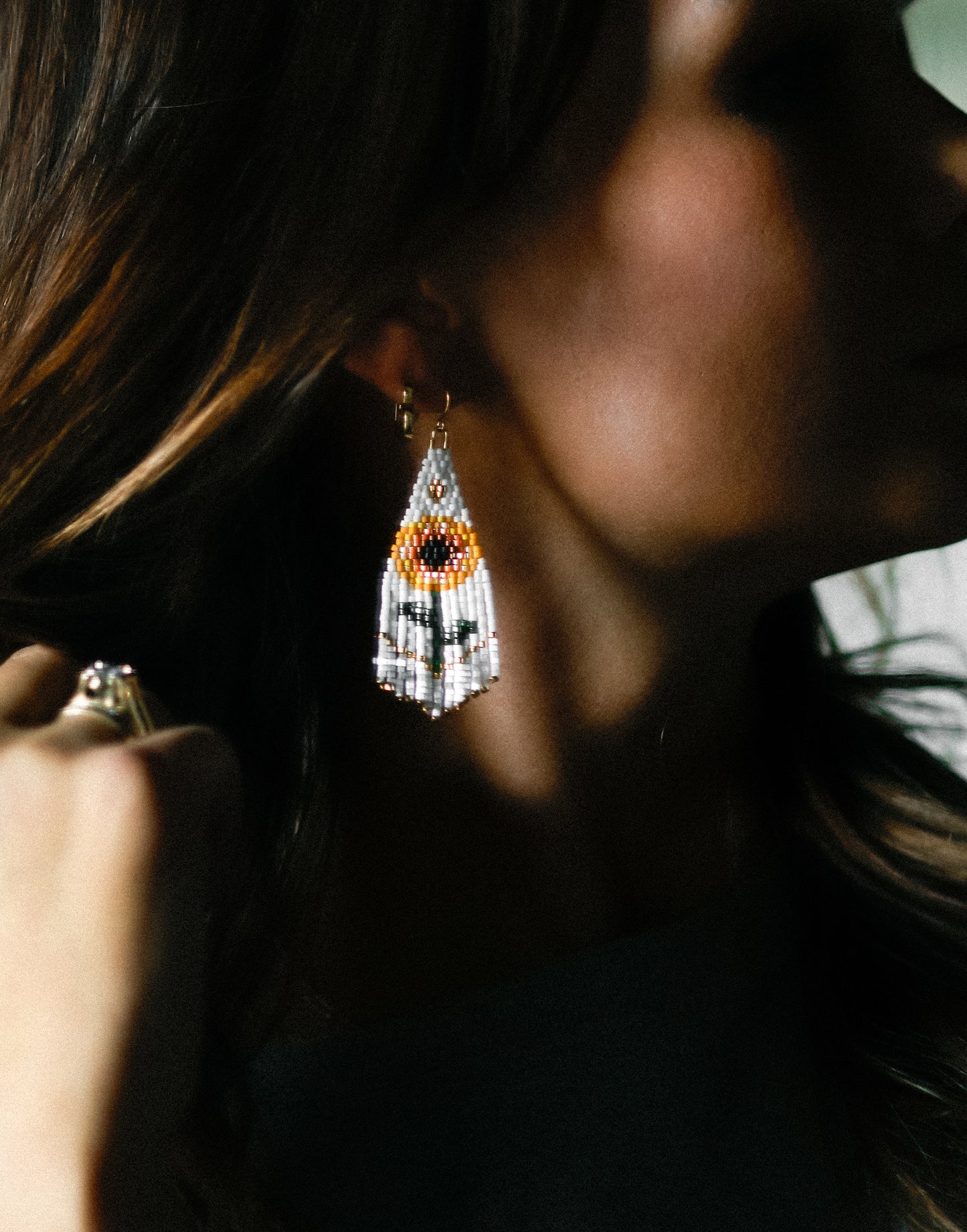 Close-up of a person wearing beaded earrings with a blurred background