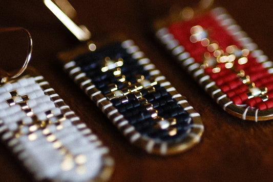 Three beaded earrings in blue, white, and red on a wooden surface.