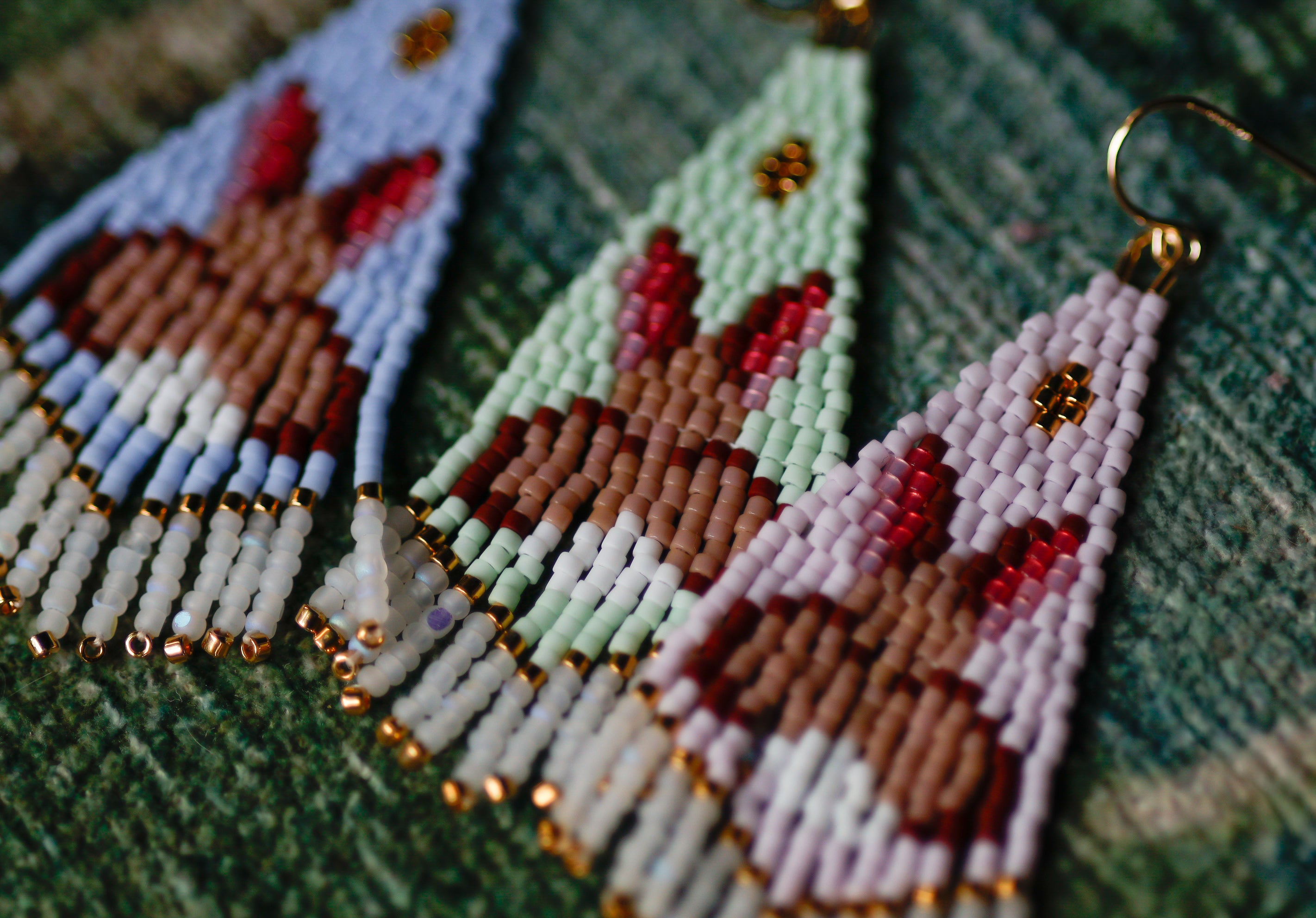 Close-up of beaded earrings with bunny design on a textured fabric background