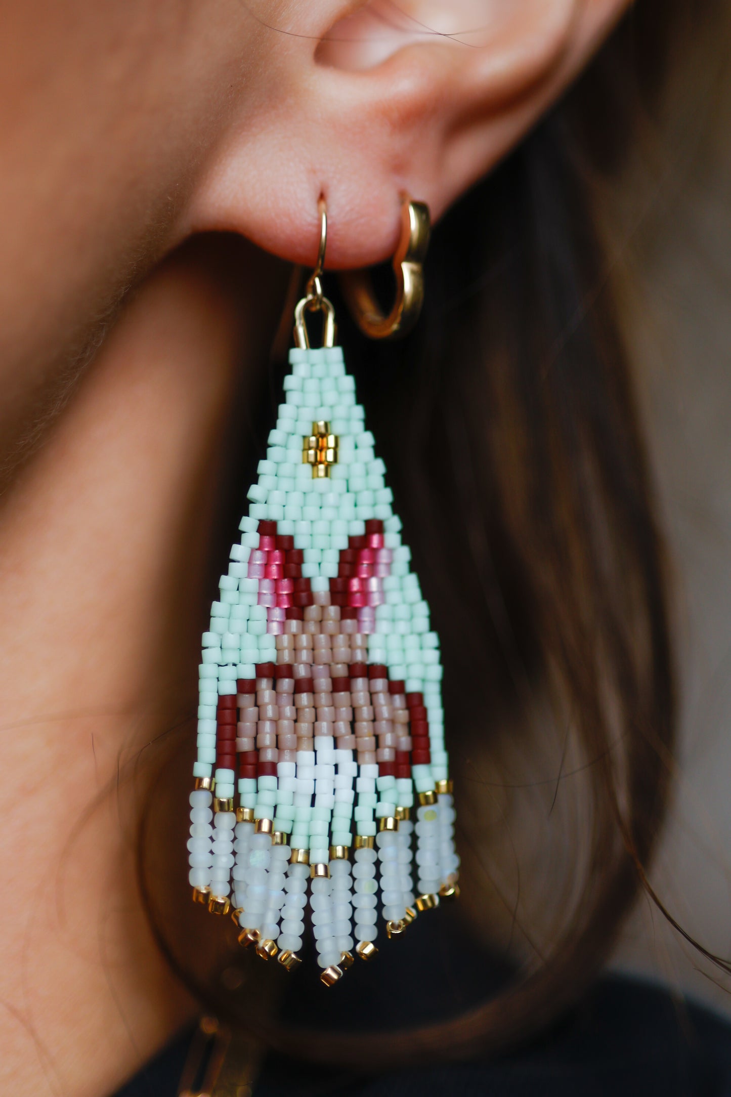 Close-up of a person wearing beaded bunny earrings with a blurred background