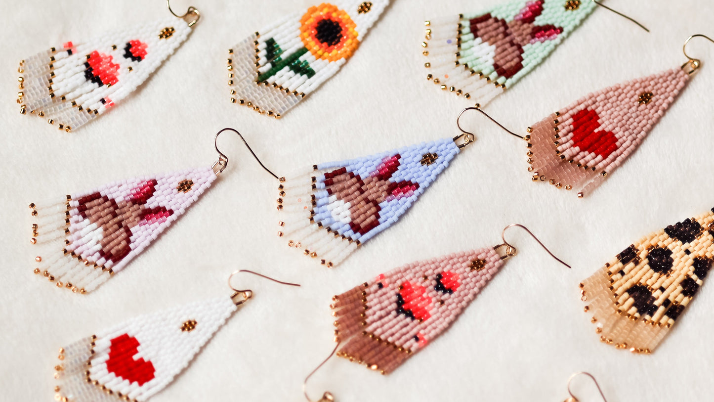 Various handcrafted beaded earrings with intricate designs on a light background