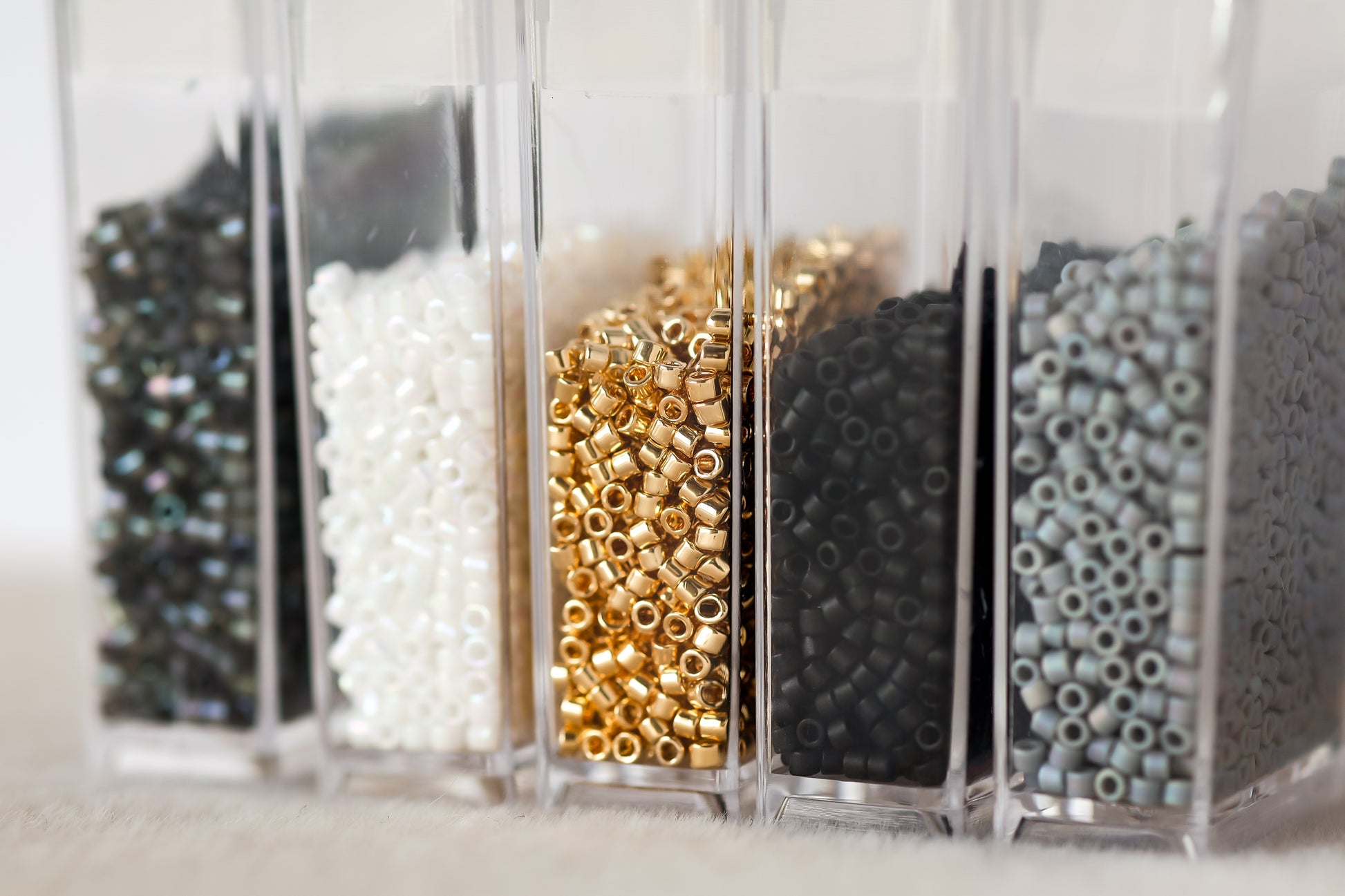 Clear containers with various types of beads on a light background