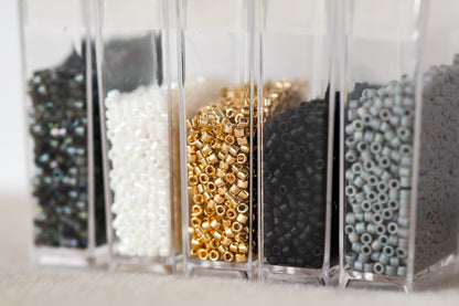 Clear containers with various types of beads on a light background