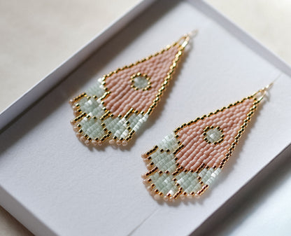 Pair of geometric handmade beaded earrings with pink and gold design on a white background