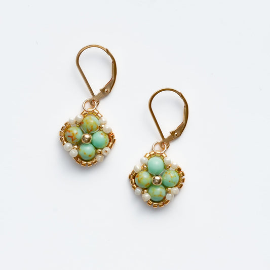 Pair of handmade, beaded earrings with green gemstones and gold accents on a white background