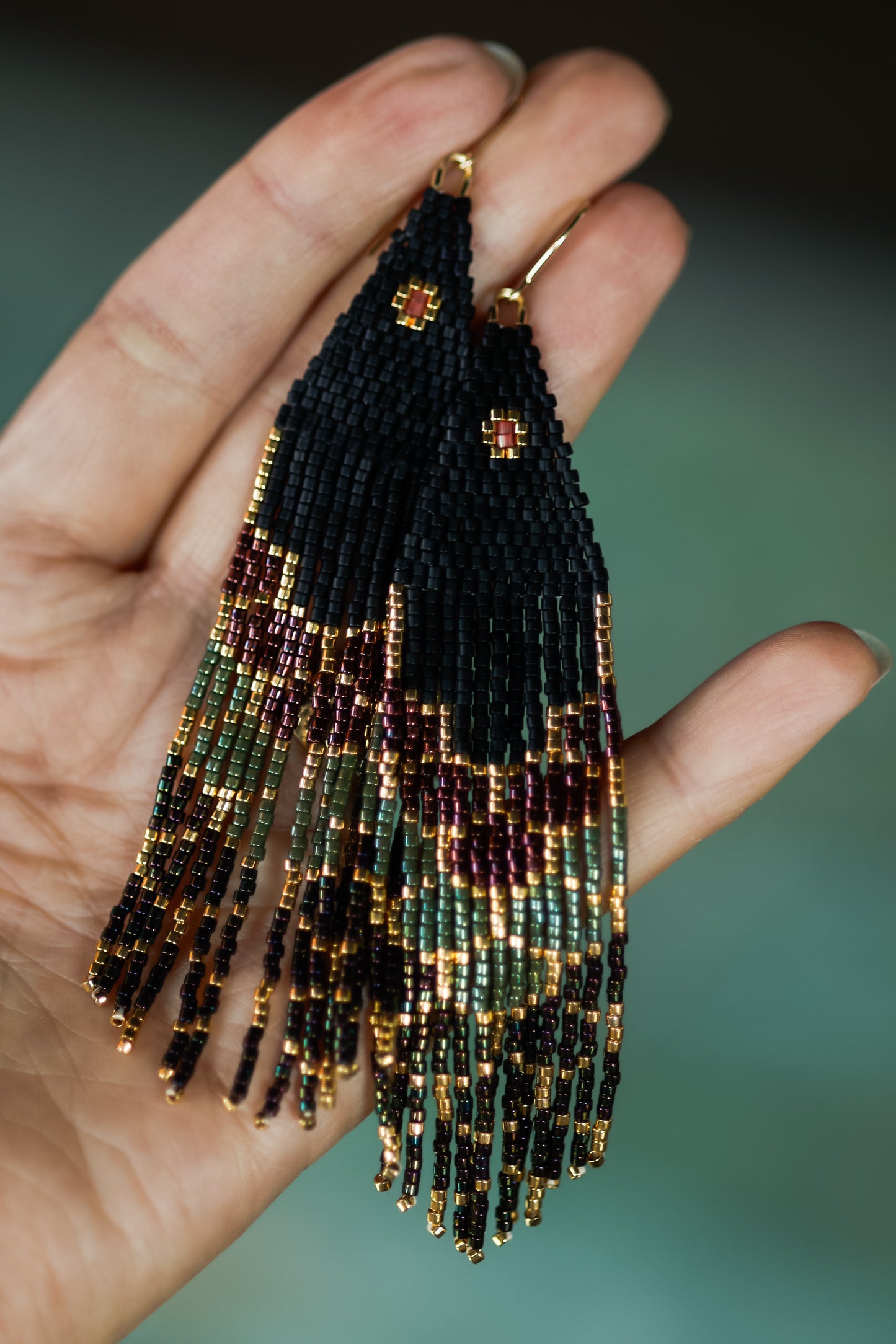 Beautiful, handmade beaded earrings held in a hand with a blurred background