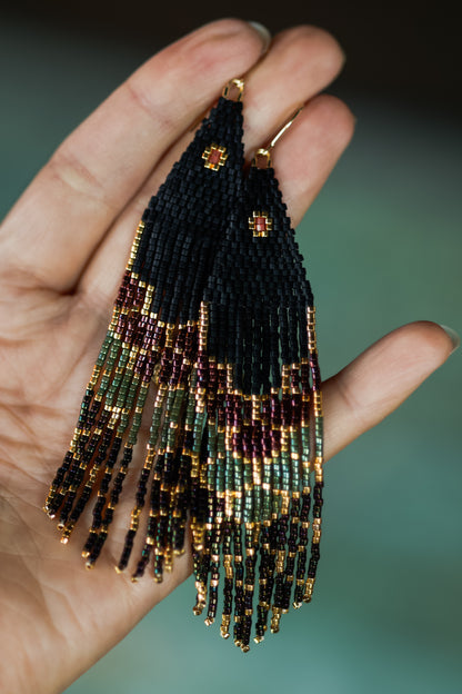 Beautiful, handmade beaded earrings held in a hand with a blurred background