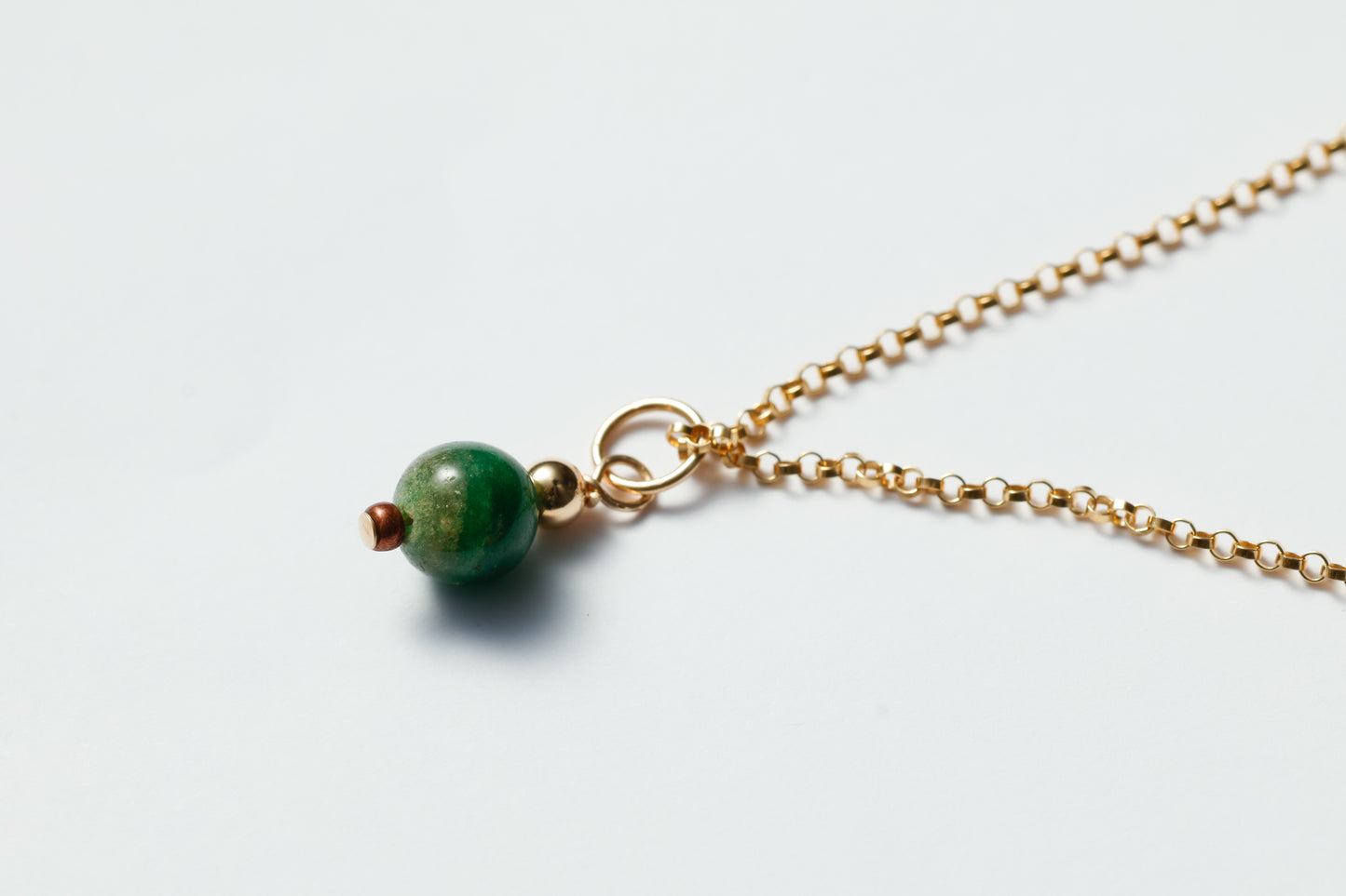 Necklace with a green bead on a light gray background