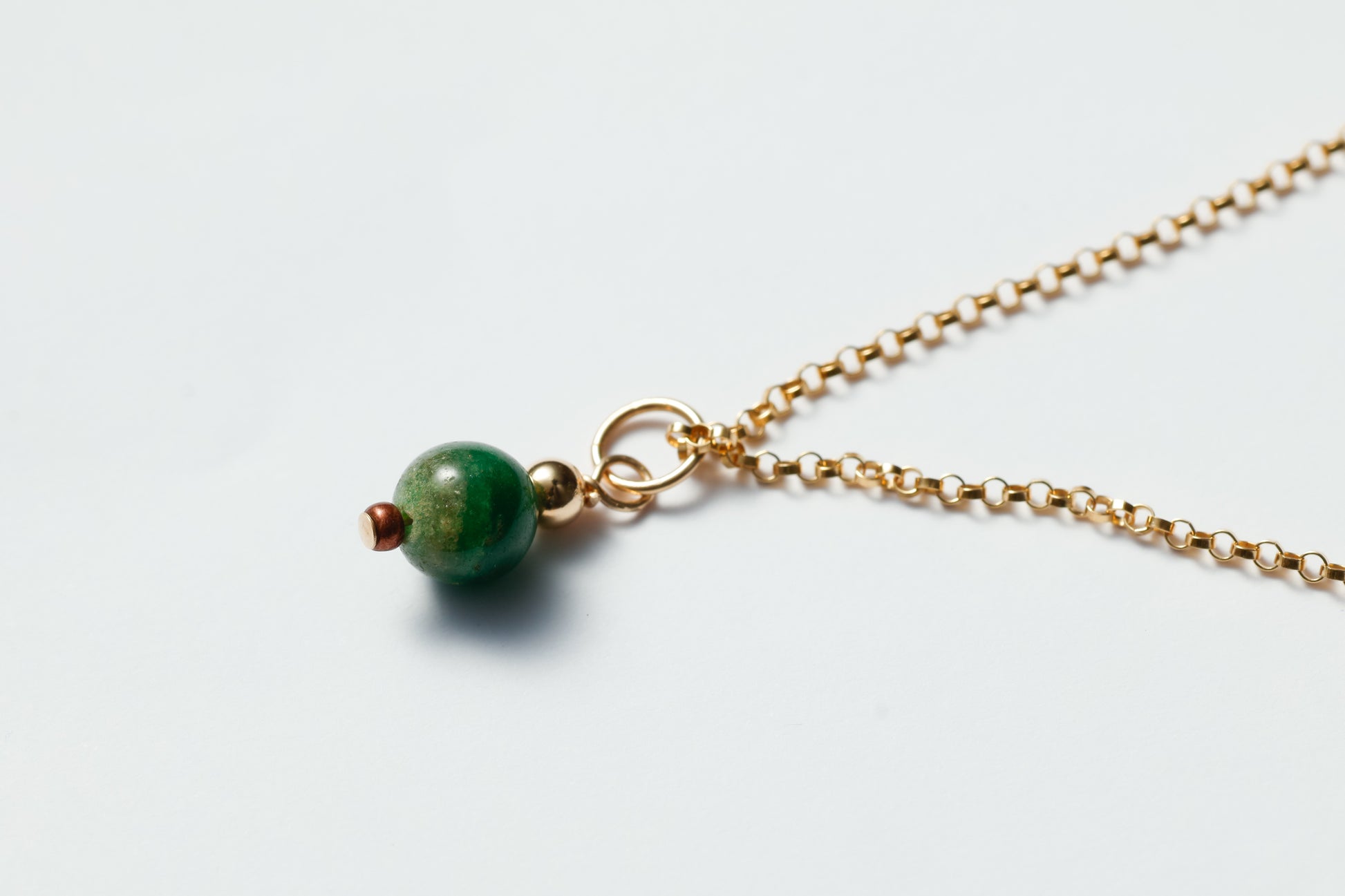Necklace with a green bead on a light gray background