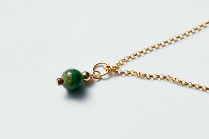 Necklace with a green bead on a light gray background