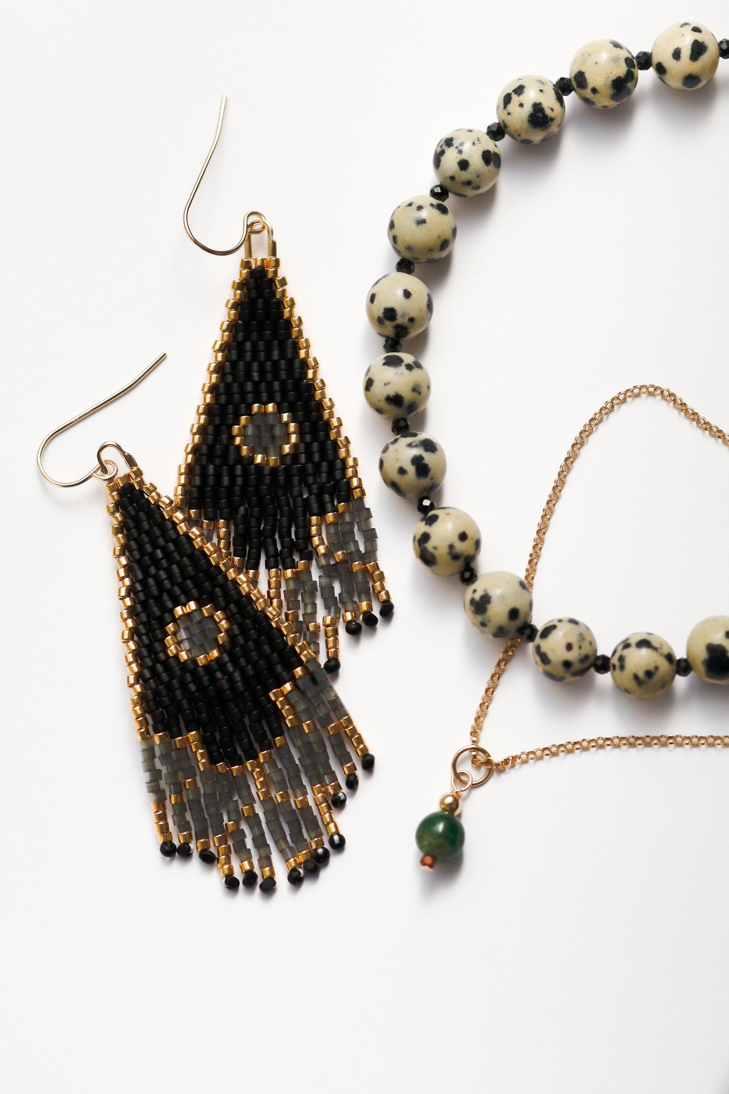 Black and gold beaded earrings with a necklace featuring white beads on a white background