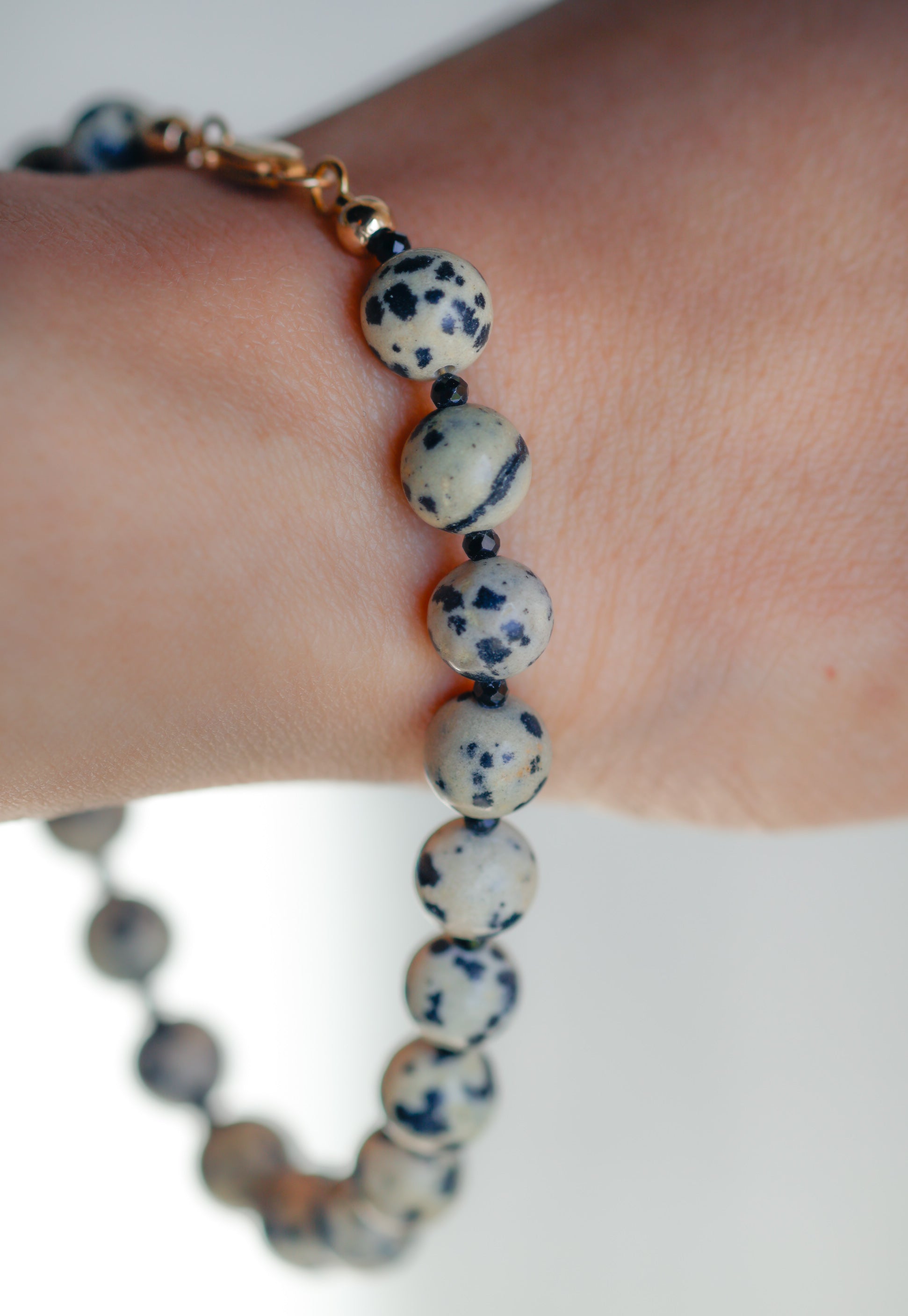 Beaded bracelet with blue and white speckled beads on a wrist against a light background