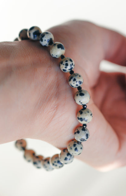 Close-up of a hand wearing a bracelet with black and white beads on a white background